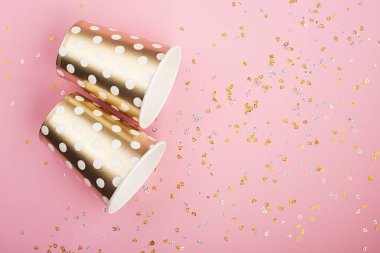 Konfeti, kağıt moda bardak narin pembe bir arka plan üzerinde evrensel popüler festival arka plan pembe altın. Kavram herhangi parlak proje eğlenceli. Yatay, kopya alanı,