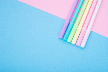 Çok renkli kalemler, keçeli kalemler, işaretçileri, narin pembe ve mavi moda ileti örneği, iki renkli substrat iki ton ile evrensel parlak arka plan. Üstten Görünüm. Yatay. Metin için yer,