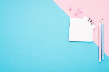 Boş defter ya da not etmek üstünde pembe ve mavi arka plan ile bir çift renk ileti örneği. Yaratıcı minimalizm mahkeme kavramı. Üstten Görünüm, düz yatıyordu.