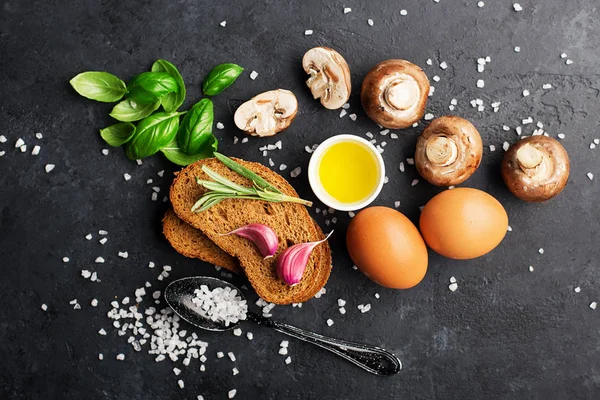 Ingredientes de una nutrición saludable. Preparación del desayuno. Huevos, pan, tomates, albahaca, salchichas, sal, champiñones, setas. Sobre un fondo oscuro, vista superior Piso Comida confortable para toda la familia . —  Fotos de Stock