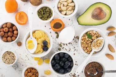 Sağlıklı bir kahvaltı için Malzemeler, fındık, yulaf ezmesi, keten tohumu, kurutulmuş meyve, avokado, yumurta, quinoa, mısır gevreği, çilek, meyve, yaban mersini, badem ceviz mevsiminde doğal organik gıda kavramı