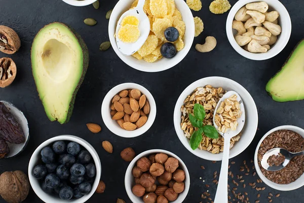Ingredients for a healthy breakfast, nuts, oatmeal, flaxseed, dried fruit, avocado, egg, quinoa, cornflakes, berries, fruits, blueberry, almonds walnuts The concept of natural organic food in season — Stock Photo, Image