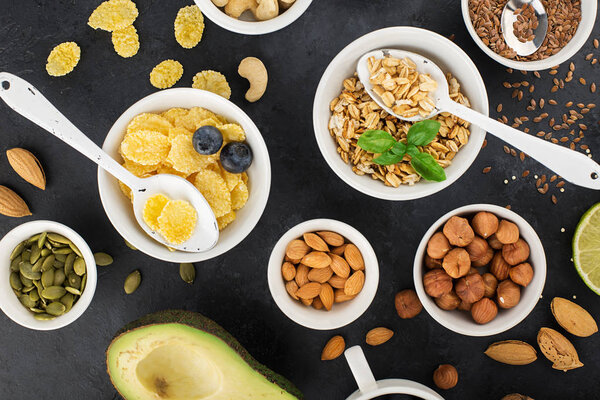 Ingredients for a healthy breakfast, nuts, oatmeal, flaxseed, dried fruit, avocado, egg, quinoa, cornflakes, berries, fruits, blueberry, almonds walnuts The concept of natural organic food in season