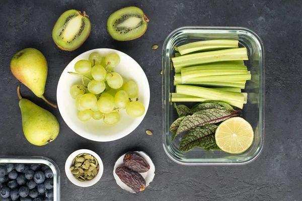 Gezonde voeding verse ingrediënten groenten fruit bessen zaden. Glazen bakjes voor de lunch met sappige selderij, limoen, sla, zuring, kiwi, druiven... — Stockfoto