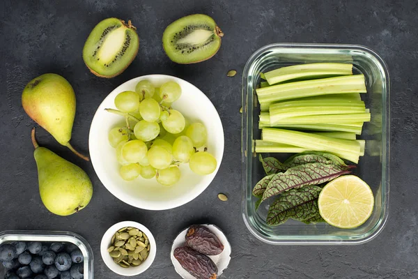 Gezonde voeding verse ingrediënten groenten fruit bessen zaden. Glazen bakjes voor de lunch met sappige selderij, limoen, sla, zuring, kiwi, druiven... — Stockfoto