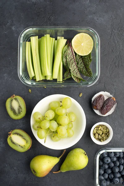 Alimentation saine ingrédients frais légumes fruits baies graines. Conteneurs en verre pour le déjeuner avec céleri juteux, citron vert, laitue, oseille, kiwi, raisins ... Images De Stock Libres De Droits