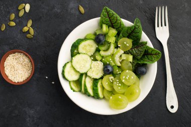 Sağlıklı yeşil yiyecek. Sulu kereviz, salatalık, üzüm, yabanmersini, marul, detoks salatası. Etsiz yemek. Üst görünüm.