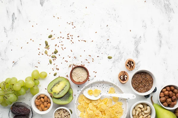 Ingrediënten voor een gezond ontbijt van volkoren ontbijt in noten, vruchten, bessen, cornflakes, granola, superfood, quinoa, vlas zaden, bosbessen, druiven. — Stockfoto