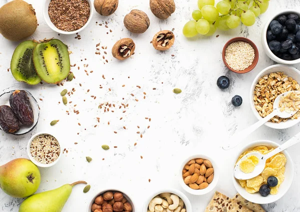 Ingredients for a healthy breakfast of whole grain breakfast in nuts, fruits, berries, cornflakes, granola, super food, quinoa, flax seeds, blueberries, grapes.