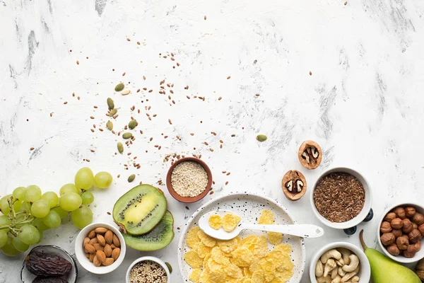 Ingredients for a healthy breakfast of whole grain breakfast in nuts, fruits, berries, cornflakes, granola, super food, quinoa, flax seeds, blueberries, grapes.