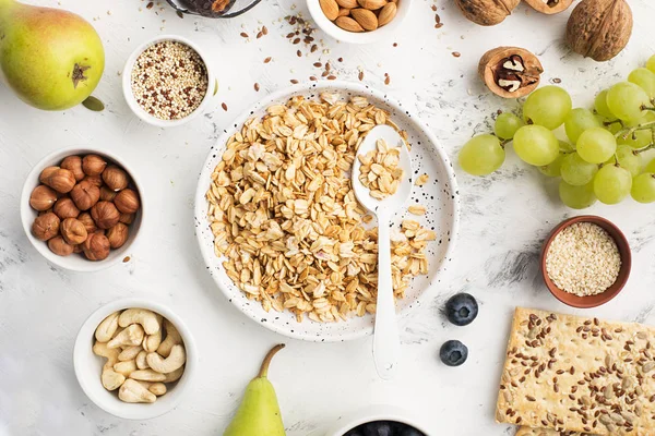 Ingredientes para un desayuno saludable de cereales integrales en frutos secos, frutas, bayas, copos de maíz, granola, súper comida, quinua, semillas de lino, arándanos, uvas . —  Fotos de Stock