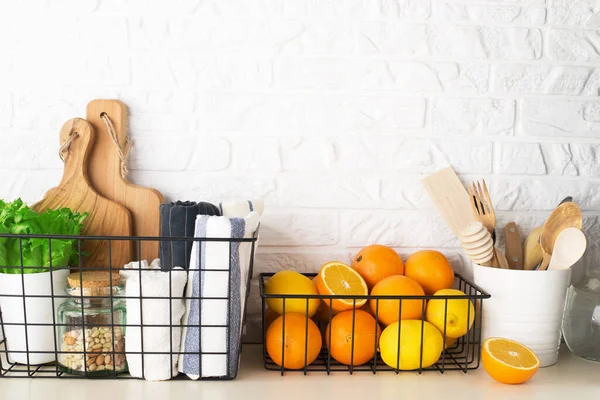 Regal in einer weißen Küche mit frischem Obst, Kräutern, Besteck, Küchenutensilien, Werkzeug, Textilien, Süßwasser in einer Karaffe. Haus, Familie, Einfachheit, Stockfoto