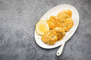 Beyaz tabakta patates kızartmalı ev yapımı balık köftesi.