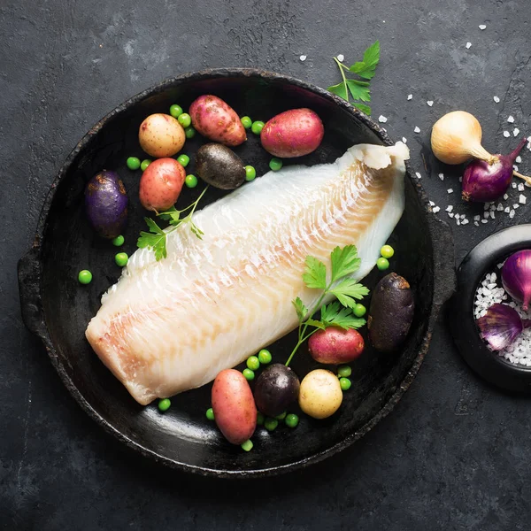 Cod white fish potatoes dish ingredients for healthy comfortable home food. Raw white fish fillet in a baking dish on a dark background. Top view., Royalty Free Stock Images