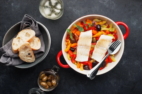 パプリカ トマト 白ワインのおいしい魚のシチュー 有機野菜とタラの切り身の白い海の魚 オリーブ 玉ねぎ ニンジン トマト 昼食のためのベーキング皿のカプセシウム トップ表示 ロイヤリティフリーのストック画像