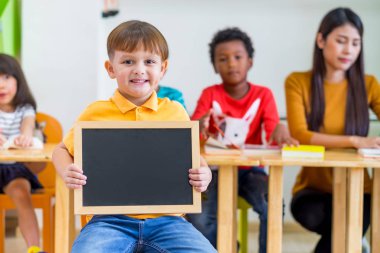 Çocuk holding blackboard ile okul Word'e geri çeşitlilik arkadaşları ve arka plan, anaokulu Okulu, öğretmen ile alay kadar metin eklemek için kara tahta çocuk