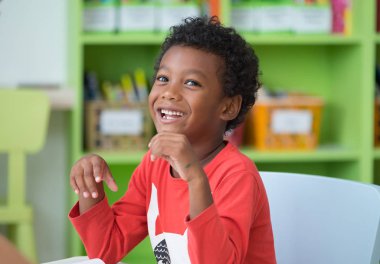 Afro-Amerikan etnisite çocuk anaokulu okul öncesi classroom.happy emotion.education kavramı kitaplığında gülümseyen
