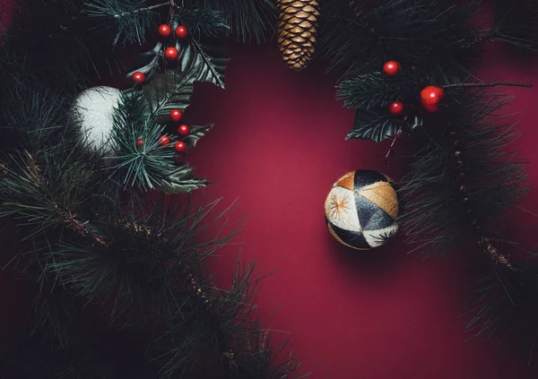赤いテーブルの背景に桜と松のコーンと花輪のクリスマス ボールとモミ枝 冬の休日のお祭りお祝いコンセプト — ストック写真
