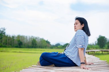 Asyalı kadın saat akşam bambu Köprüsü'nde pirinç alan çapraz bacak oturan hissediyorum rahatla ve taze deniz tarağı emotion.natural ile seyahat