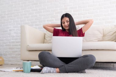 Asyalı kadın serbest kol ve kafa arkası istirahat yükseltmek ve evde oturma odasında dizüstü bilgisayar önünde gözünü kapat, zor work.work evde sakin ol
