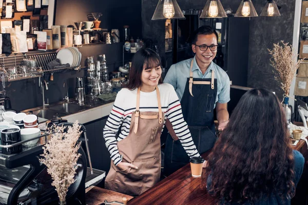 Asia barista waiter and waitress take order from customer in coffee shop,Two cafe owner writing drink order at counter bar,Food and drink business concept,Service mind concept