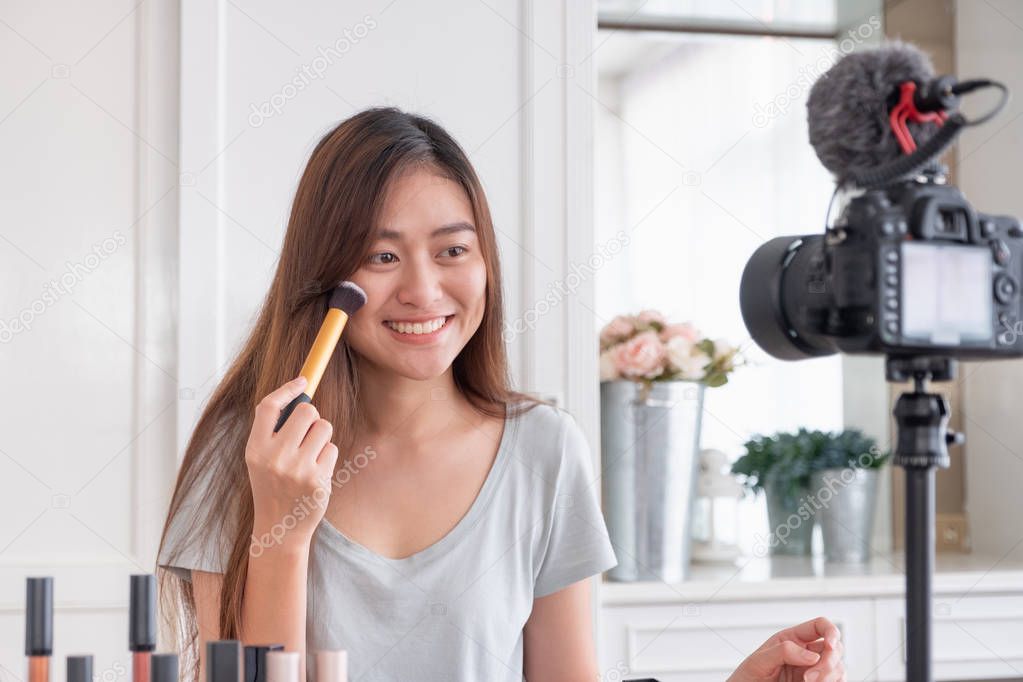 Asian young female blogger recording vlog video with makeup cosmetic at home online influencer on social media concept.live streaming viral