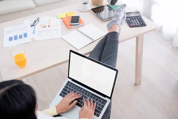 top view of woman use laptop and leg on table chill out working at home.mock up template device screen.Digital lifestyle concept.clipping path screen