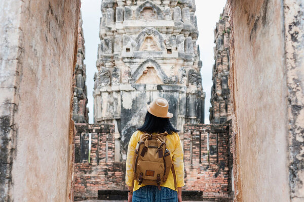 Asian tourist woman take a photo of ancient of pagoda temple thai architecture at Sukhothai,Thailand. Female traveler in casual thai cloths style visiting city concept