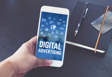 El üstünde perde siyah defter ve siyah ahşap masa, dijital teknoloji kavramı pazarlama üzerinde kredi kartı ile dijital reklam ile konuşurken telefon tutarak