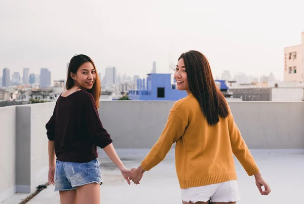 两个女同性恋夫妇牵手 一起走在屋顶上的建筑物傍晚日落时间 — 图库照片