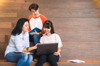 Asya genç öğrenciler ve öğretmen dizüstü bilgisayar birlikte üniversite merdiven Kütüphanesi'nde okuyan kullanarak grupları