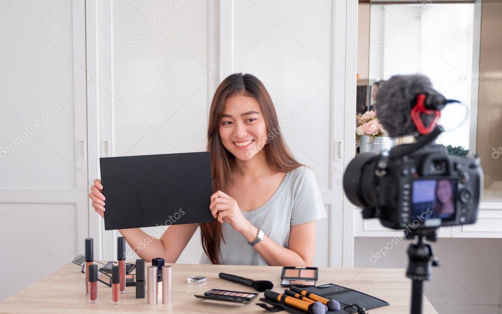 Asian young female blogger giveaway gift fan following channel while recording vlog video with makeup cosmetic at home online influencer concept.live streaming viral.mock up blackboard for your design