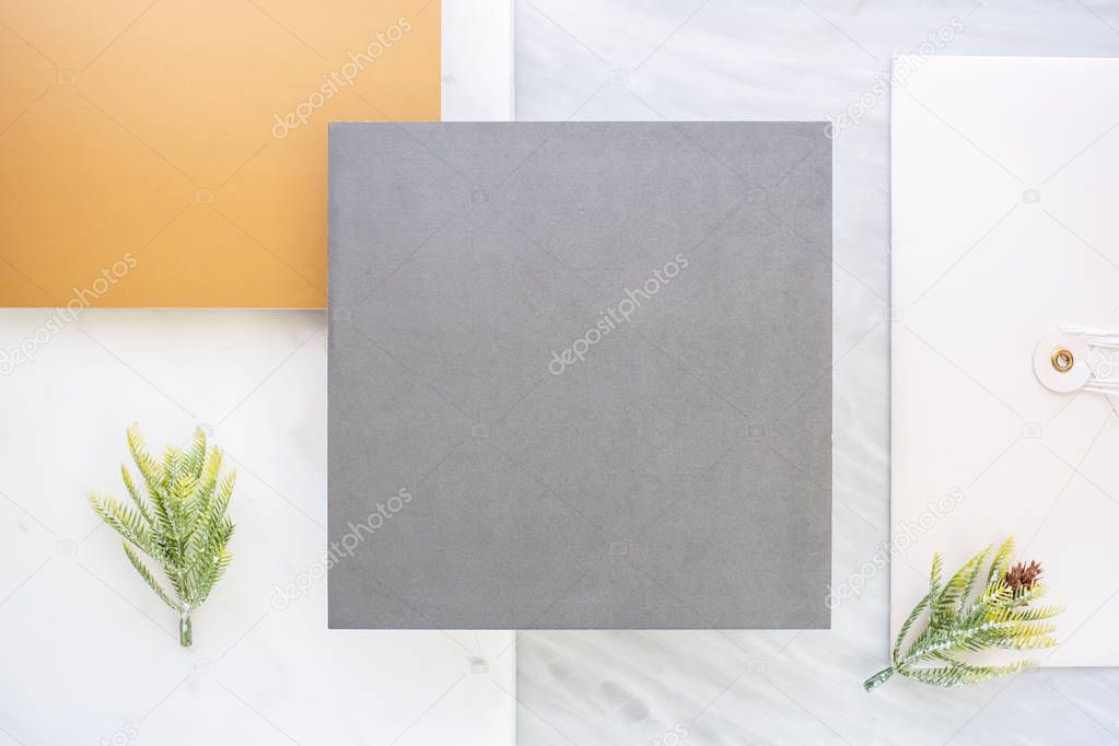 Top view of blank grey card overlap on envelop and gold card with pine leaf on two layer step of marble table top.Mock up template for display of design .luxury business items