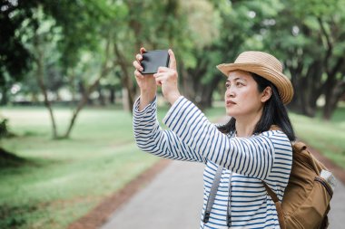 Ne zaman yağmur ormanı seyahat Asyalı kadın sırt çantası gezgin kullanım telefon almak fotoğraf. Tatil tatil concept.journey lifestyle.solo seyahat
