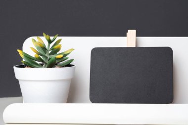 Siyah küçük tahtaya modern kalem kutusu ve tablo ve koyu gri beyaz tencerede yeşil bitki ofis masası duvar, tasarım veya metin görüntülemek için alanı kadar alay