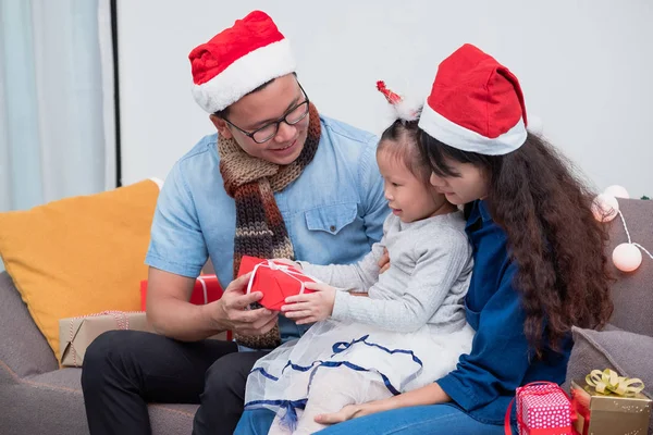 Happy family Asia family wear santa claus hat exchange Christmas gift box at house xmas party,Holiday celebrating festive concept