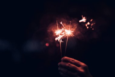 Yanan maytap patlama bir siyah bokeh arka planda tutan gece, tatil kutlama olay parti, karanlık vintage sesi el