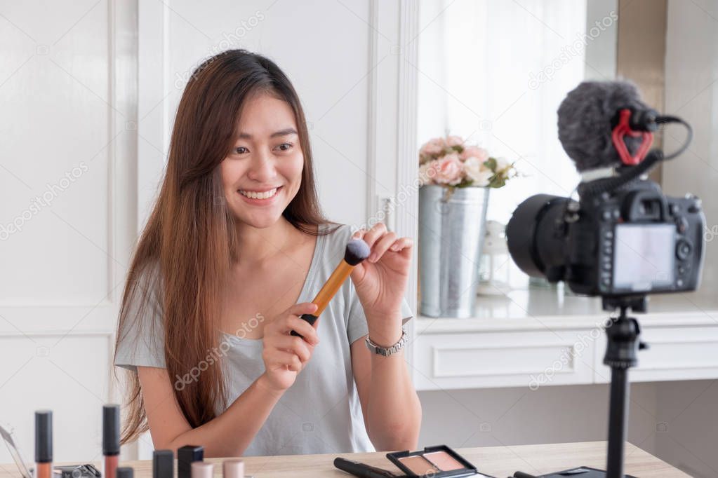 Asian young female blogger recording vlog video with makeup cosmetic at home online influencer on social media concept.live streaming viral 