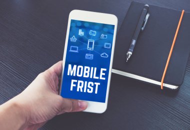 Hareket eden telefon ile mobil ilk sözcük ve özellik simge siyah ahşap masa arka plan, dijital pazarlama kavramı, ofis masası üstünde defter üzerinde tutan el.