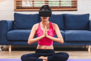 Asyalı kadın kullanım virtural gerçeklik gözlük kulaklık yoga poz online oturma odası katta home.self öğrenme, eğitim için