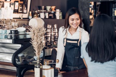 Asyalı kadın barista aşınma jean önlük sayaç gülümseme duygu, Cafe Restoran hizmet anlayışı, sahibi küçük iş kavramı ile bar müşteriye hizmet kahve fincanı holding.
