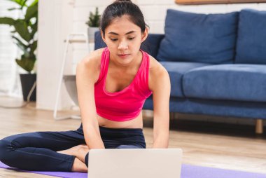 Asyalı kadın eğitim video onine dizüstü ve kendi kendine eğitim yoga poz evde oturma odası tabanında arama. Teknoloji ile sağlıklı yaşam tarzı