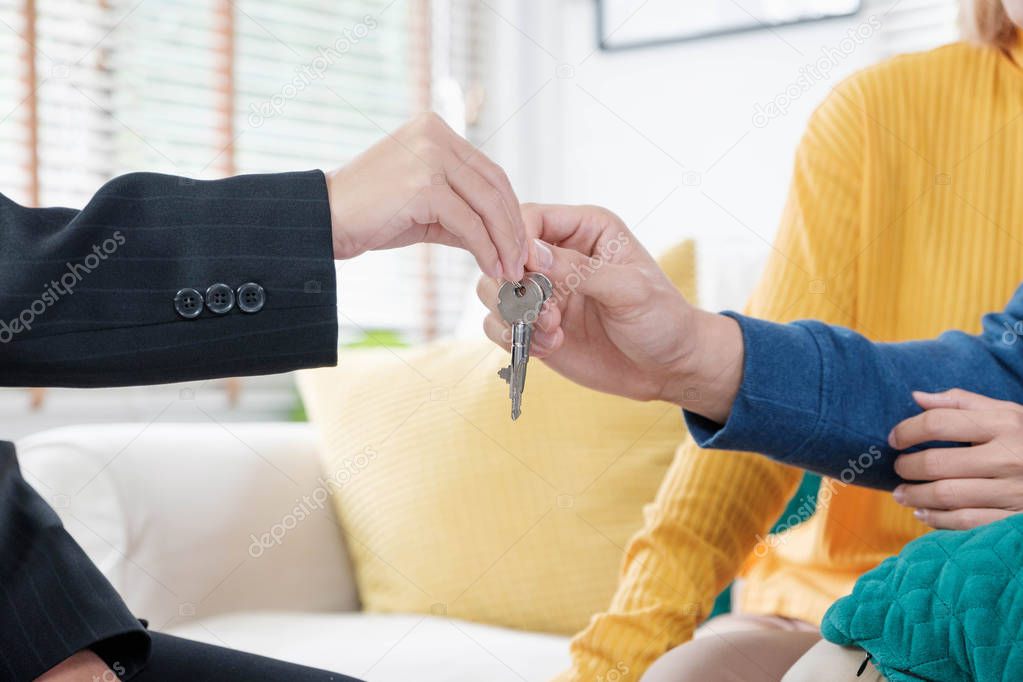 Asian happy couple getting key with realtor agent with happy moment at new home.buying new house real estate