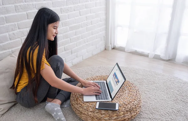 Asiatico femmina sit con ginocchia su sul pavimento utilizzando laptop vedere sociale — Foto Stock