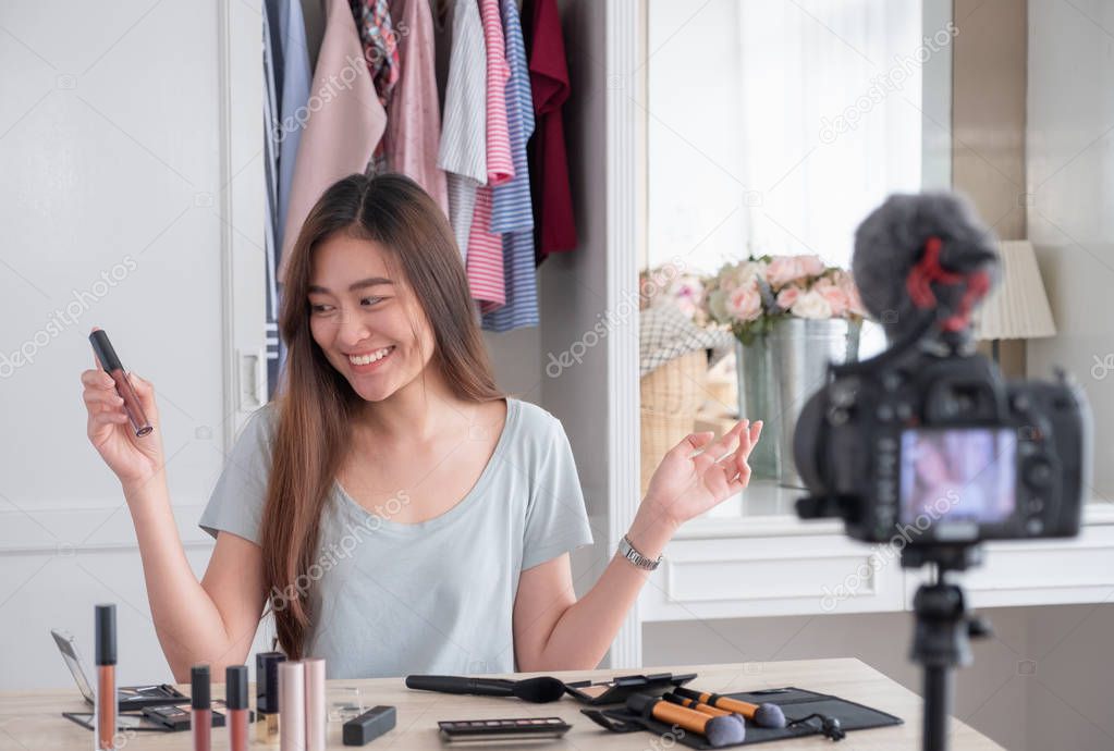 Asian young female blogger recording vlog video with makeup cosm