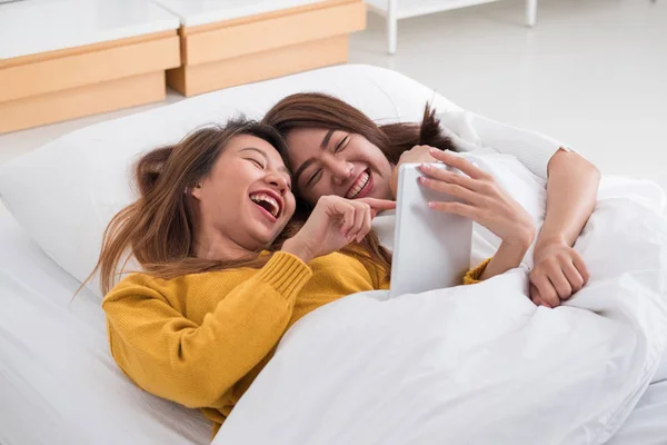 Pasangan lesbian Asia berbaring di tempat tidur menggunakan tog komputer tablet — Stok Foto