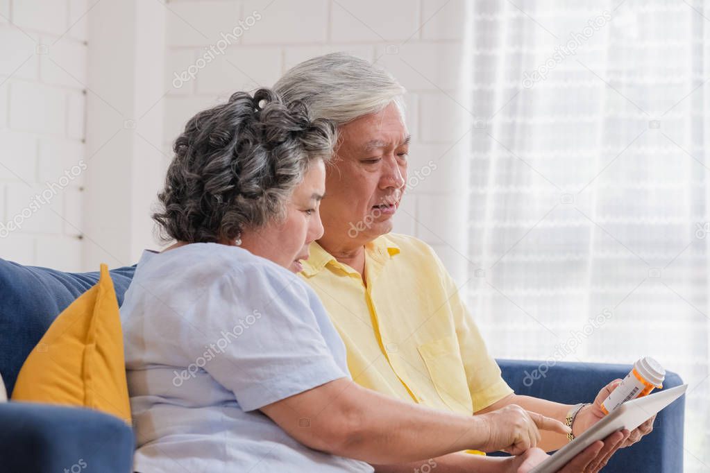 Asian senior couple use tablet searching prescription of pill wh