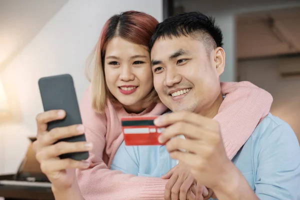 Asian couple use mobile shopping online with credit card togethe