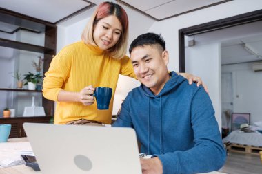 Asyalı çift evde masada dizüstü bilgisayarda canlı video izlerken.love