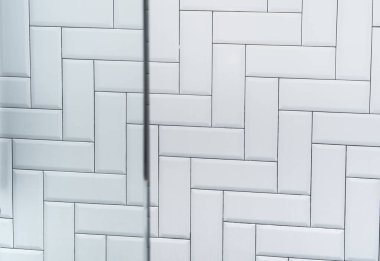 Beyaz seramik tuğla karo duvar ve cam, modern soyut teks.